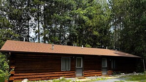 Una cabana de fusta amb un camí de grava i un bosc al fons.