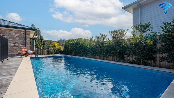 A swimming pool with a wooden deck and a brick wall. - Holiday Crescent – Spacious, stylish retreat with pool, perfect (Berry)