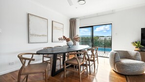 A modern dining area with a round table, wooden chairs, and a view of a swimming pool. - Holiday Crescent – Spacious, stylish retreat with pool, perfect (Berry)