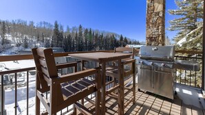 Un'area esterna con un barbecue e sedie che si affaccia su un paesaggio innevato.