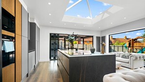 Een moderne keuken met een centraal eiland, een zithoek met een bank, en uitzicht op een achtertuin met een speelruimte.