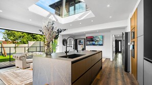 Een moderne keuken met een centraal eiland, een ingebouwd spoelbak en een groot raam boven het eiland.