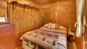 A wooden-paneled room with a bed, a dresser, and a small table. - Pet-Friendly Vergas Cabin on Loon Lake w/ Dock! (Vergas)