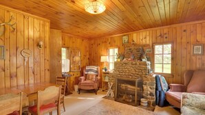 A cozy wooden cabin interior with a stone fireplace, wooden dining table, and comfortable seating. - Pet-Friendly Vergas Cabin on Loon Lake w/ Dock! (Vergas)