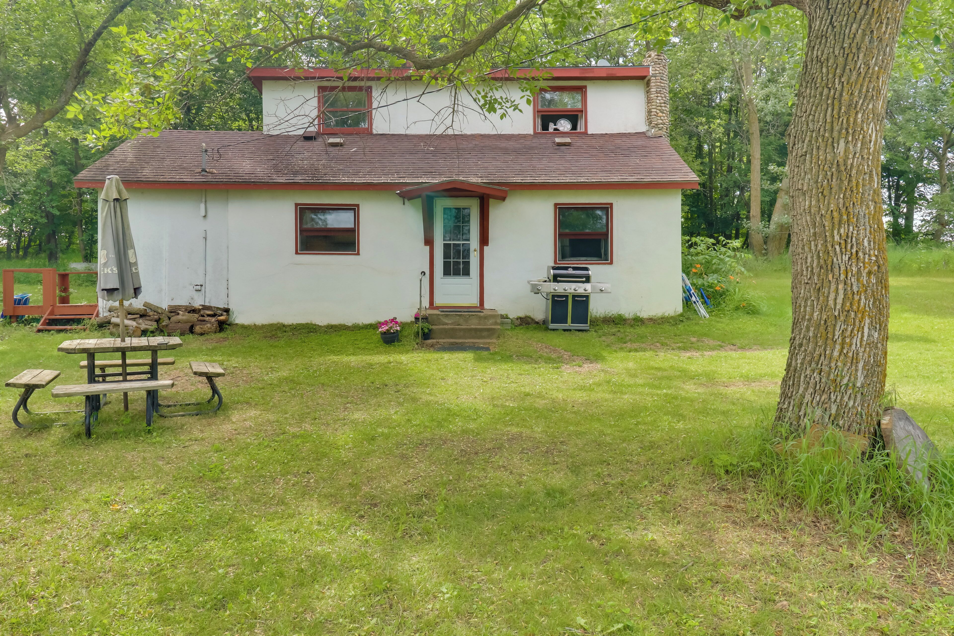 A two-story house with a front porch, a grill, and a picnic table.