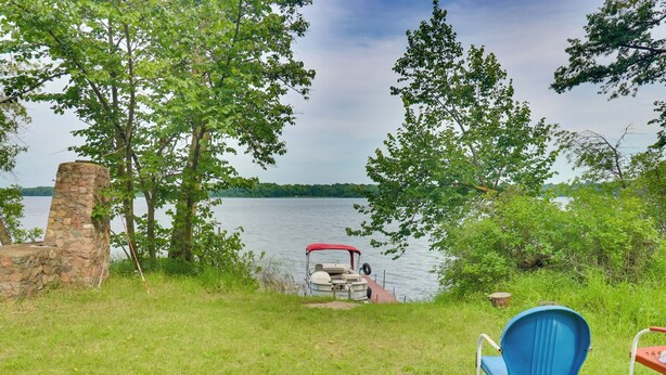A lakeside view with a stone structure, a red and white boat, and a blue chair. - Pet-Friendly Vergas Cabin on Loon Lake w/ Dock! (Vergas)