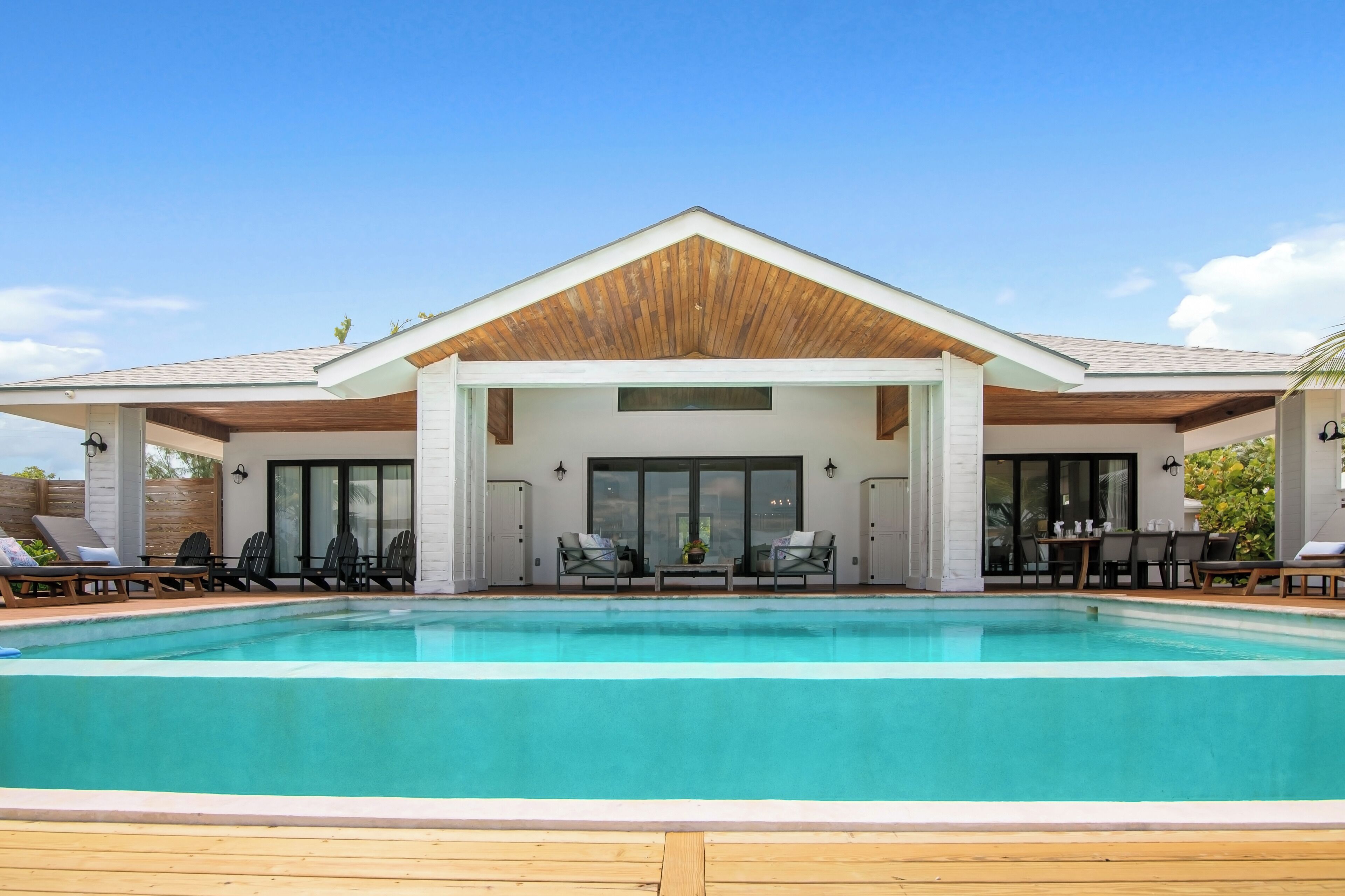 A modern house with a swimming pool, outdoor seating, and a covered patio area.