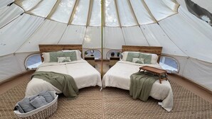 A symmetrical tent with two beds, each with pillows and a blanket, and a woven rug on the floor. - Secret Sycamore– Private Stargazing Glamping Tent with Fire Pit & Open Skies (Bunker)