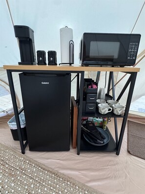 A compact kitchenette with a black refrigerator, a microwave, a coffee maker, and a small sink. - Secret Sycamore– Private Stargazing Glamping Tent with Fire Pit & Open Skies (Bunker)