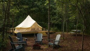 Un área de camping con carpas, sillas Adirondack y una mesa de picnic.