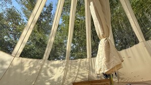 A tented accommodation with a bed, a bedside table, a lamp, and a small mirror. - Secret Sycamore– Private Stargazing Glamping Tent with Fire Pit & Open Skies (Bunker)
