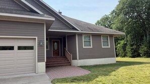 A two-story house with a garage, a front porch with steps, and a brick pathway leading to the door.