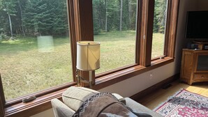 A room with large windows, a lamp, a couch, and a TV.