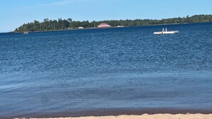 A beach with a sandy shore, a pier, and a building with a red roof in the background.