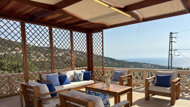 Un espace extérieur abrité, avec des meubles en bois et une vue sur la mer.