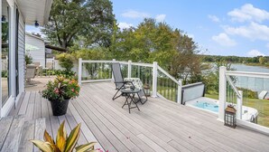 A wooden deck with a hot tub, outdoor furniture, and a view of a lake.