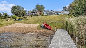 A riverside property with a dock, a red kayak, and houses in the background.