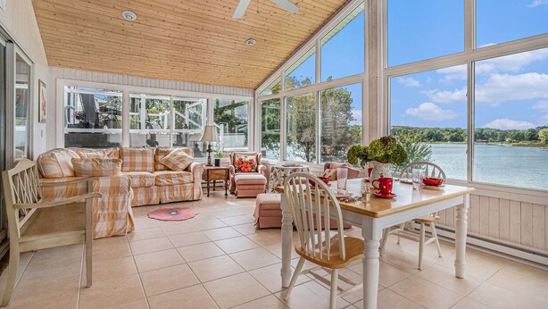 A spacious sunroom with large windows, a ceiling fan, and a wooden floor.
