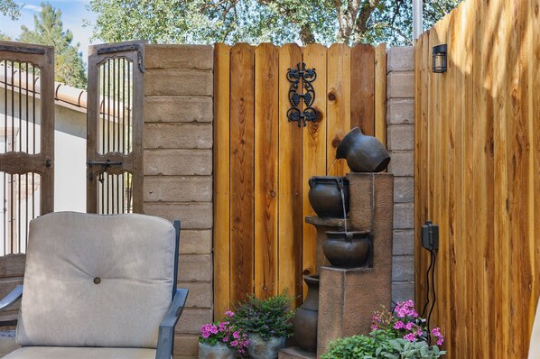 A wooden gate with a decorative metal piece, a chair, and potted plants.