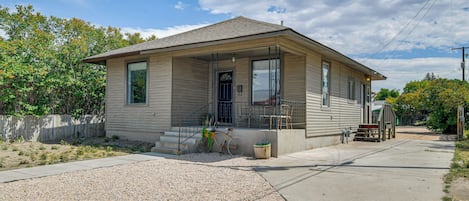 A single-story house with a front porch, a bicycle parked outside, and a gravel driveway.