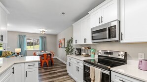 A modern kitchen with white cabinets, a stainless steel microwave, and a black stove.