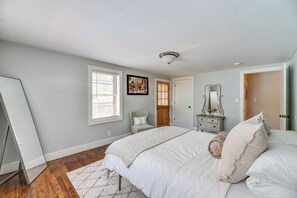 A bedroom with a large bed, a dresser, a chair, and a door.