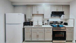 A modern kitchen with white cabinets, a built-in microwave, a stainless steel oven, and a black range hood. - 2 King Beds / 55" TV / Rainfall Shower / W/D (Philadelphia)