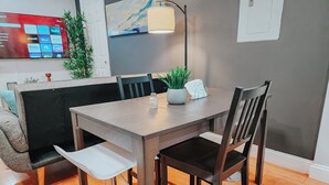 A dining area with a wooden table, four chairs, a small potted plant, and a lamp. - 2 King Beds / 55" TV / Rainfall Shower / W/D (Philadelphia)