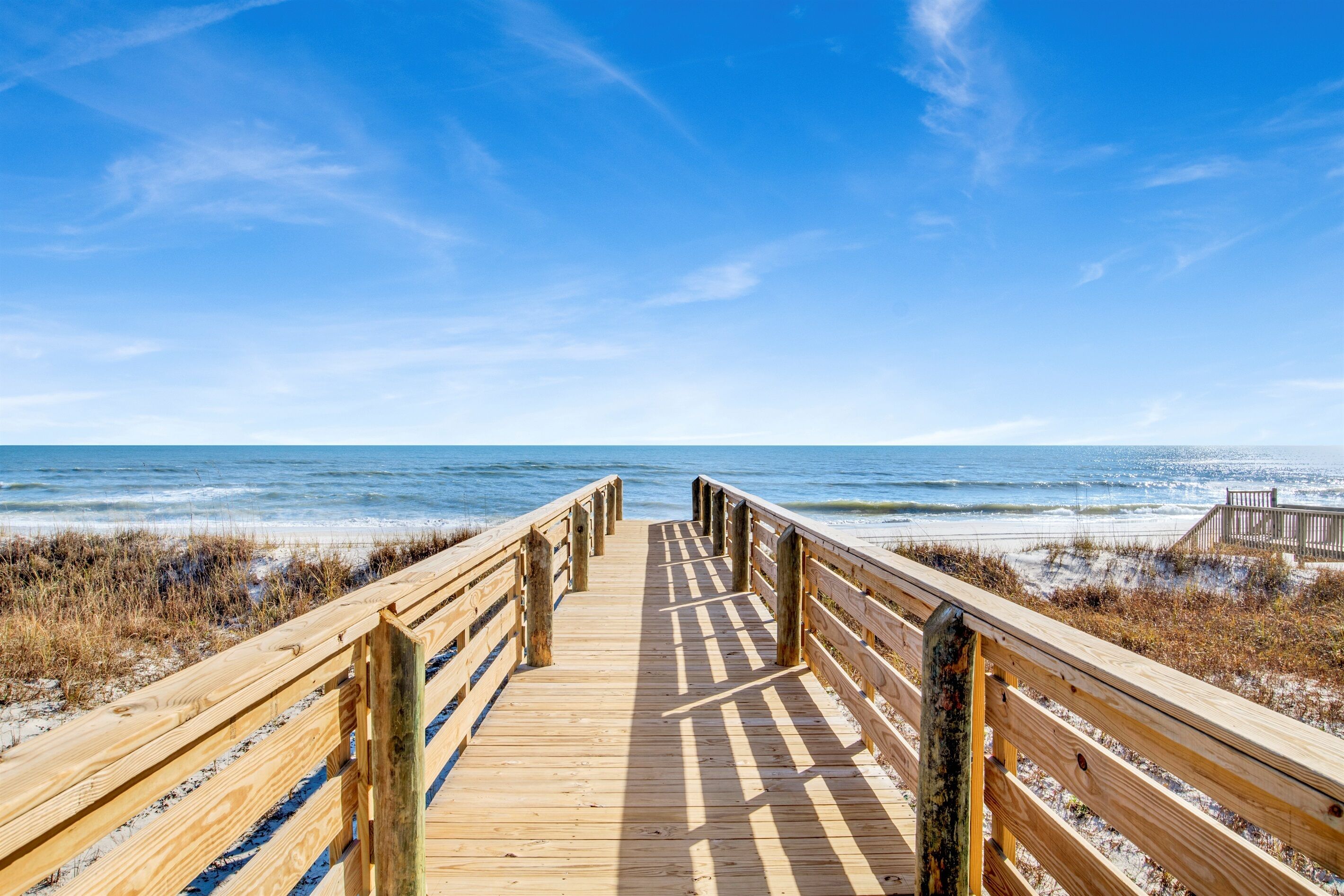 Pasarela de madera que conduce a la playa con vistas despejadas del océano.