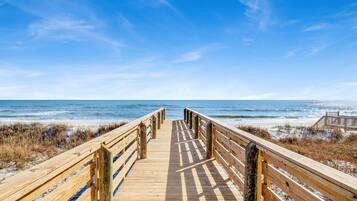 Pasarela de madera que conduce a la playa con vistas despejadas del océano.