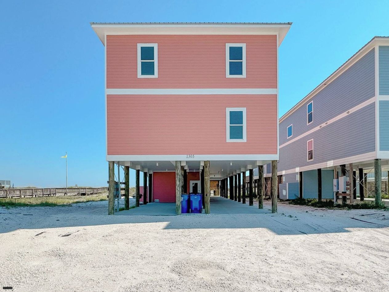 Un edificio de dos pisos con fachada roja y un porche cubierto.