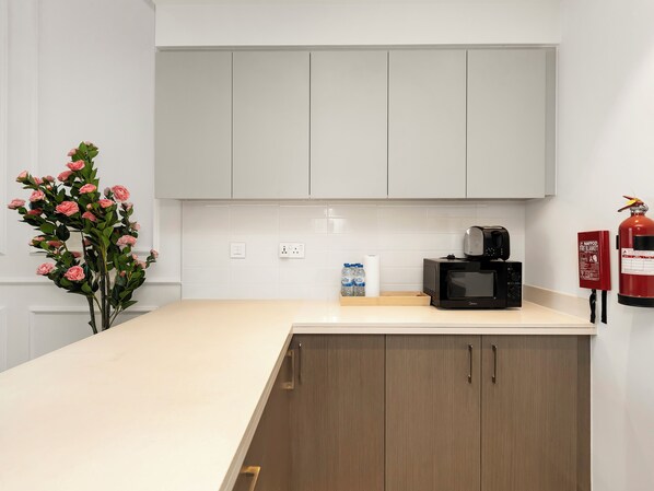 A modern kitchen with white cabinets, a microwave, and a fire extinguisher.