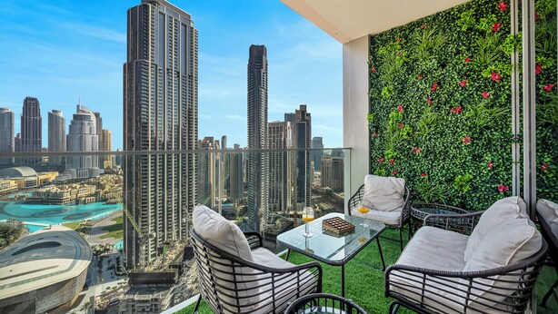 A balcony with a city view, wicker chairs, a glass table, and a green wall with plants. - Skyline Luxury I Burj Khalifa & Fountain (Dubai)