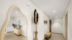 Un passadís amb un mirall gran, un vas decoratiu i obra d'art a la paret.