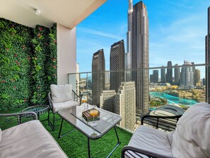 A balcony with a glass table, white chairs, and a green wall with plants. - Skyline Luxury I Burj Khalifa & Fountain (Dubai)