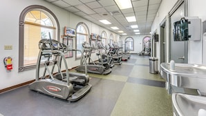 Une salle de sport équipée de tapis de course, de vélos elliptiques et d’une fontaine à eau.