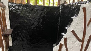 A bathroom with a black bathtub, white tiles, and a wooden chair. - Maloka Napu-Ecodestinos (Puerto Nariño)