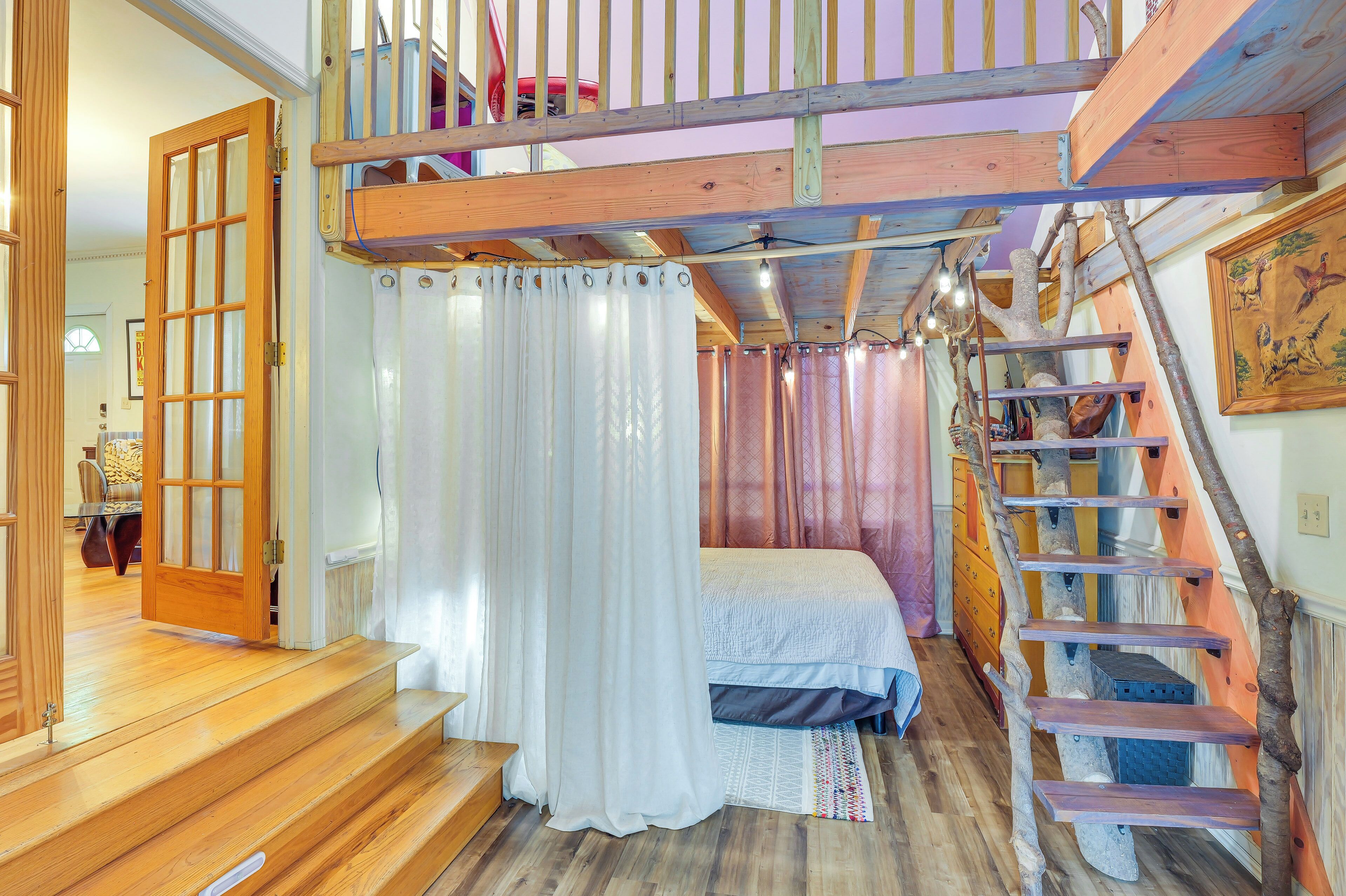 Ein Schlafzimmer mit Holztreppe, einem Bett und Blick ins Freie.