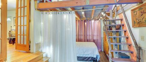 Ein Schlafzimmer mit Holztreppe, einem Bett und Blick ins Freie.