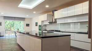 Una cocina moderna con gabinetes blancos, encimera negra y una isla grande.