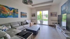 Una sala de estar moderna con un sofá gris, una mesa de centro, un televisor y obras de arte en las paredes.