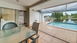 Ein Tisch mit Glasplatte, Stühle, ein Pool und Blick ins Grüne.