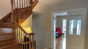 A wooden staircase leading to a room with a lamp, a chair, and a door leading to another room with a view of trees. - Direct Bike Access, WaterPark, S’mores nights (Bromont)