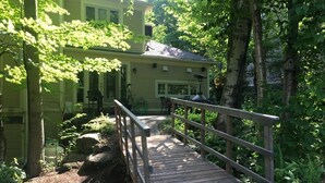 A wooden bridge leading to a house surrounded by trees. - Direct Bike Access, WaterPark, S’mores nights (Bromont)