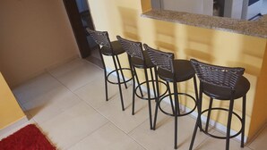 A kitchen area with four black bar stools, a red rug, and a granite countertop.