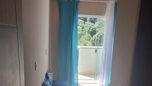 A room with a blue sofa, a sliding glass door leading to a balcony, and a tiled floor.