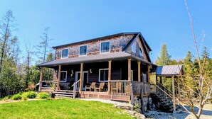 A two-story wooden house with a porch, a covered staircase, and a small deck.