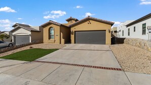 A residential house with a garage, a small front lawn, and a stone retaining wall.