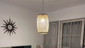 A bedroom with a large bed, a hanging light fixture, a wall-mounted sun decoration, and a wooden wardrobe. - Studio in the countryside near village with all amenities (Sénas)