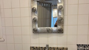 A bathroom with a sink, mirror, and decorative tiles. - Studio in the countryside near village with all amenities (Sénas)